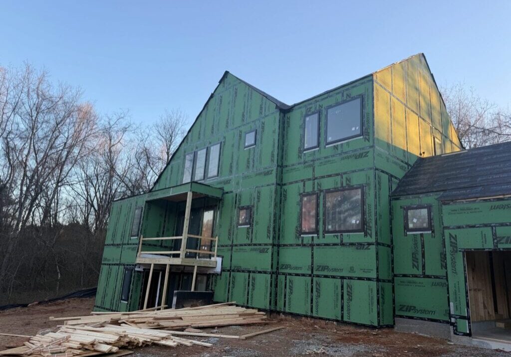Two-story home under construction with green ZIP System sheathing and new windows installed